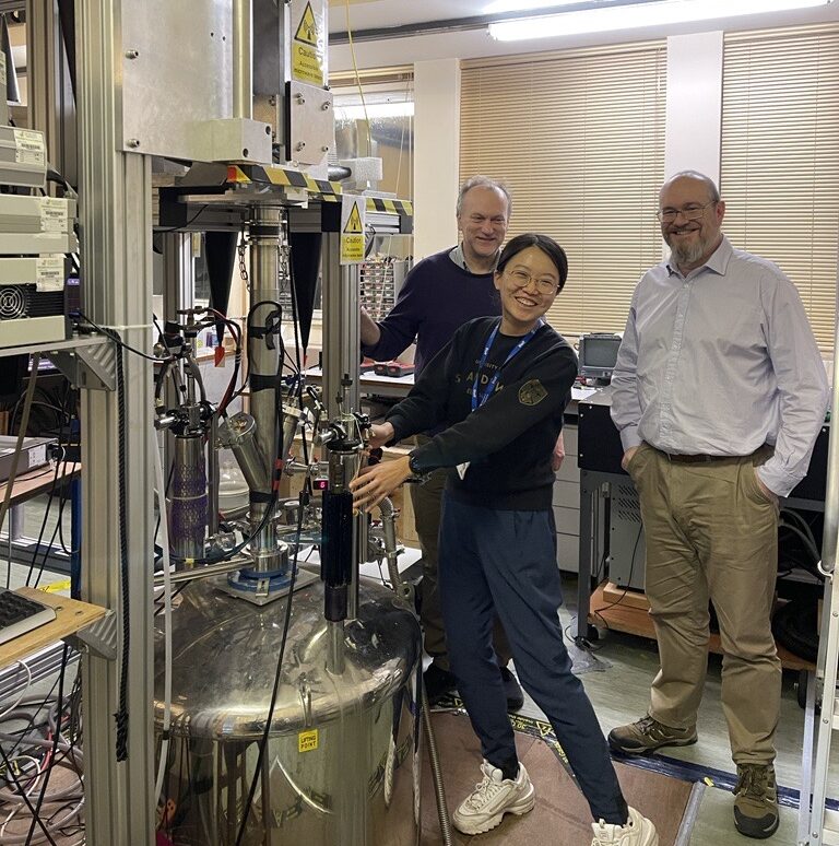 Yujie Zhao (centre), Rob Hunter (back left), Graham Smith (right) stood beside inside the HiPER lab.
